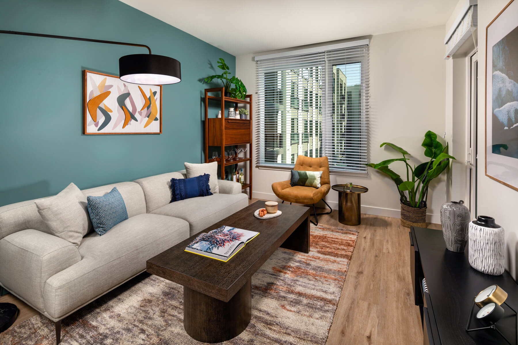 Pet-Friendly Apartments in Downtown Los Angeles, CA - Cozy Living Room With Beautiful Hardwood Floors, Vibrant Teal Accent Wall, and Window With View